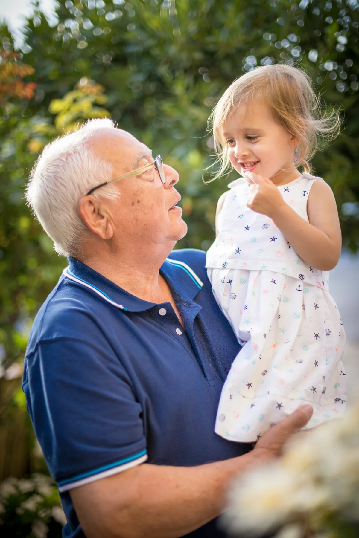 A grandfather smiling with his granddaughter in his arms