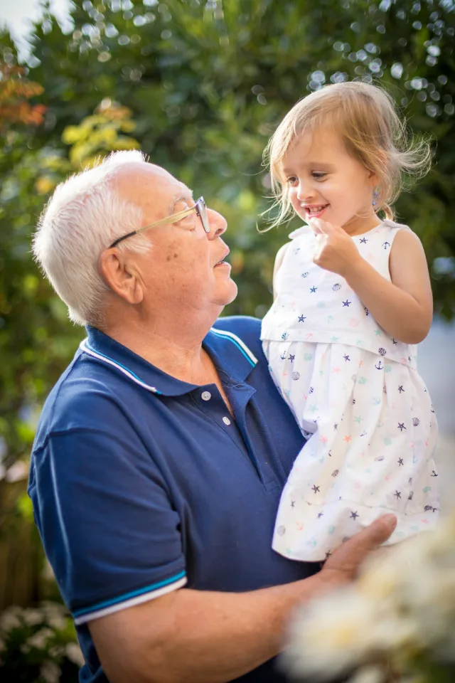 A grandfather holding his granddaughter, both smiling
